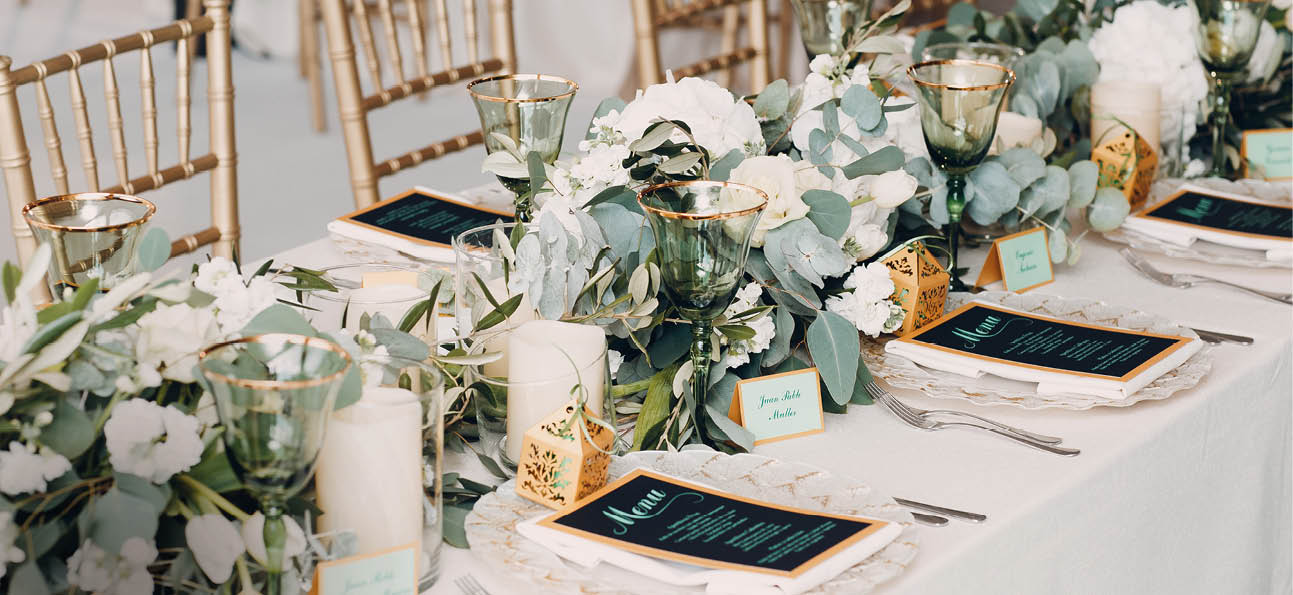 A table with a green tablecloth and a white floral centerpiece. Description generated by AI