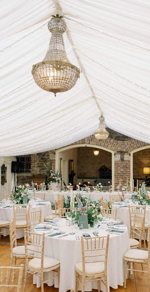 A large white tent with a gold chandelier hanging from the ceiling. Description generated by AI