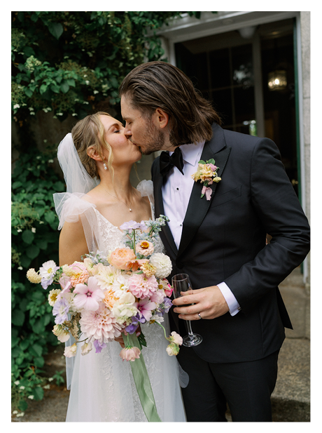 A bride and groom are kissing in a garden. Description generated by AI