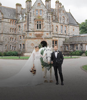 A bride and groom standing in front of a large building. Description generated by AI
