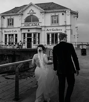 A bride and groom standing in front of a building. Description generated by AI