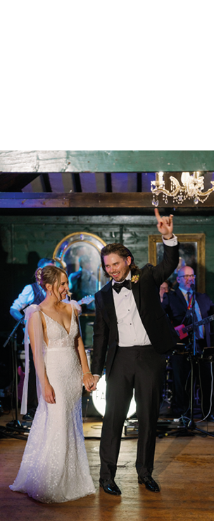 A bride and groom are dancing in a room with a chandelier. Description generated by AI