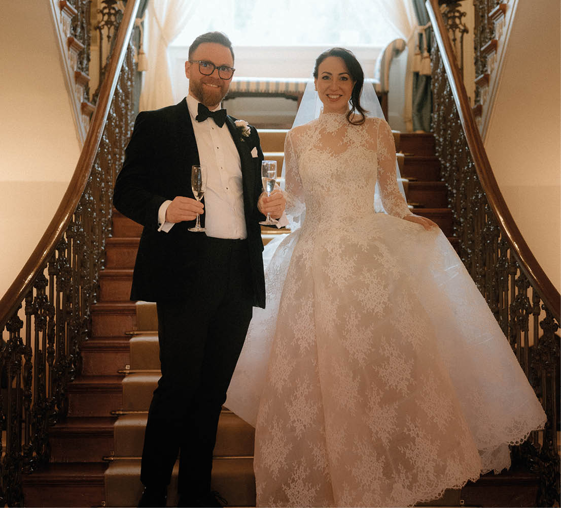 A man and woman standing on a staircase. Description generated by AI