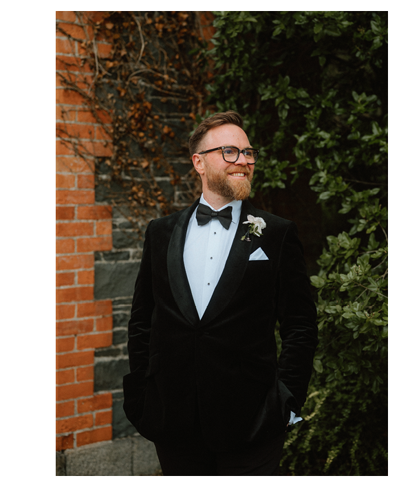 A man wearing a black suit and a bow tie. Description generated by AI