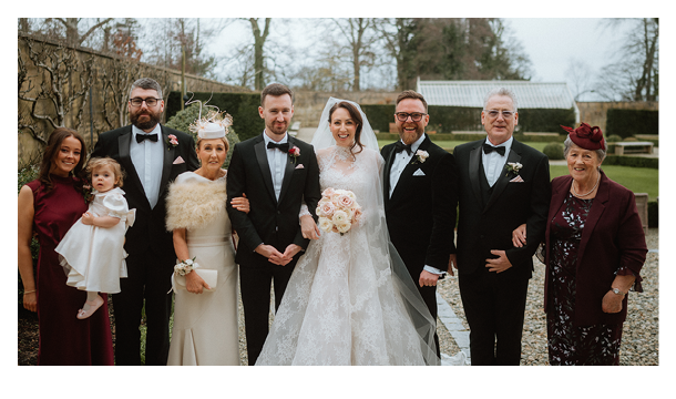 A group of people in formal wear, including a bride and groom, posing for a picture. Description generated by AI
