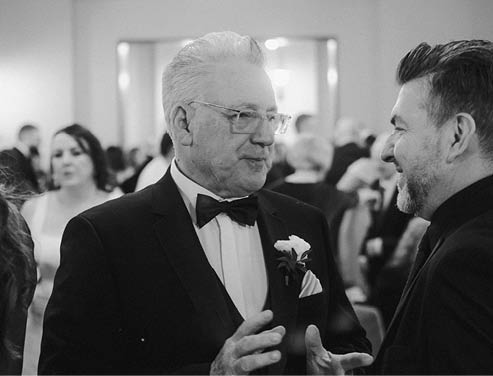 Two men wearing suits and ties are talking to each other. Description generated by AI