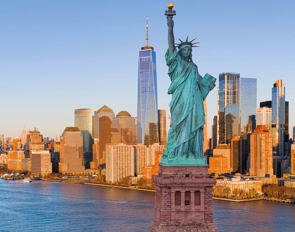 A statue of a woman holding a torch is located in a city. Description generated by AI