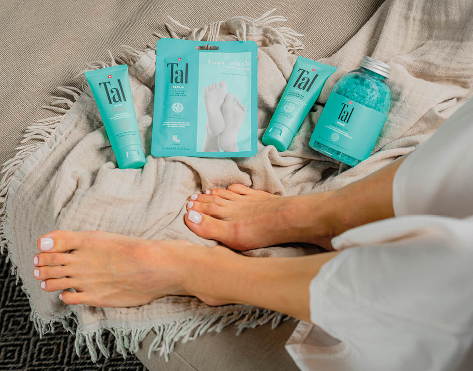 A person's feet are visible on a couch with a towel and a bottle of lotion. Description generated by AI