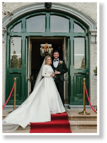A bride and groom standing in front of a green door. Description generated by AI