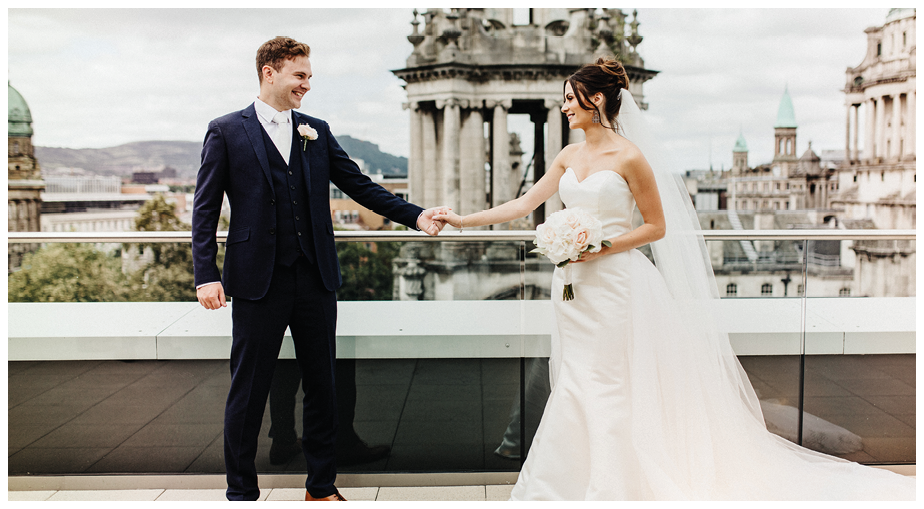A man and woman are standing on a rooftop. Description generated by AI