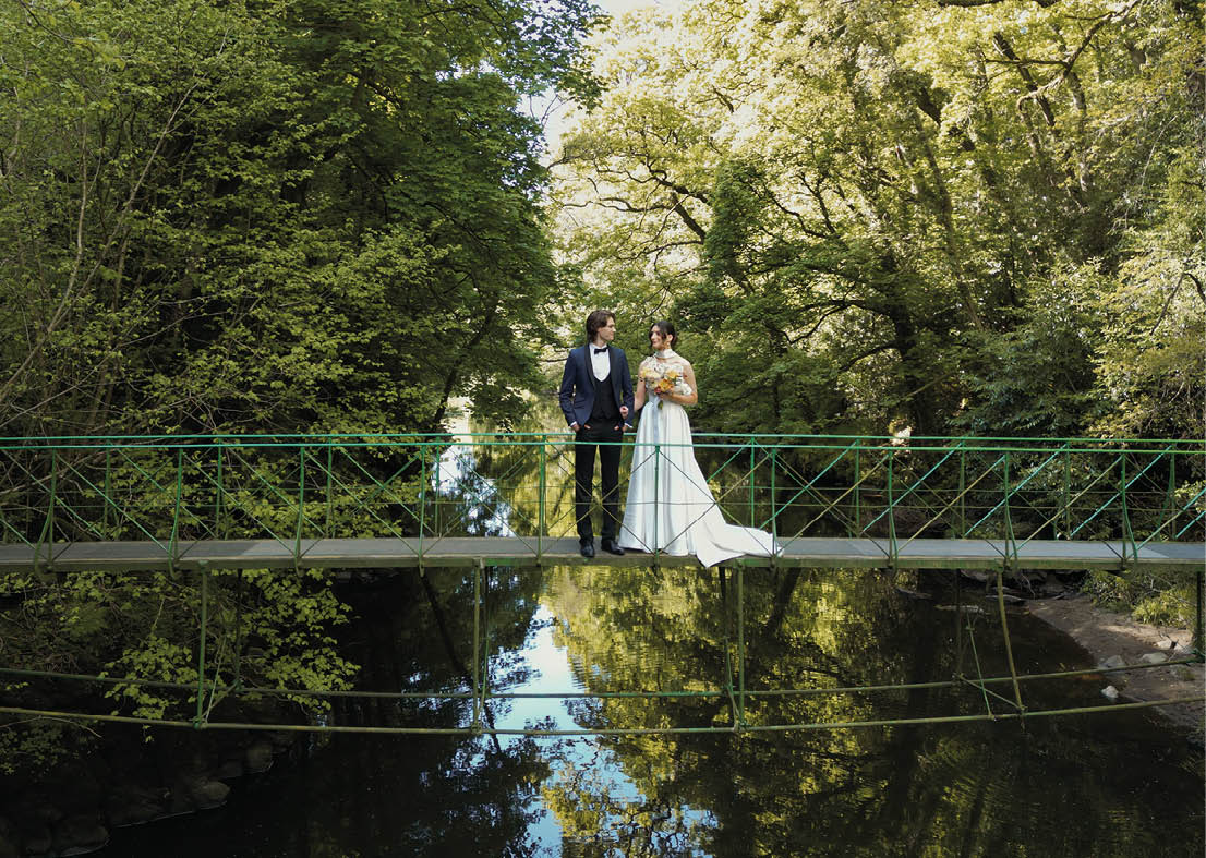 A couple standing on a bridge over water. Description generated by AI