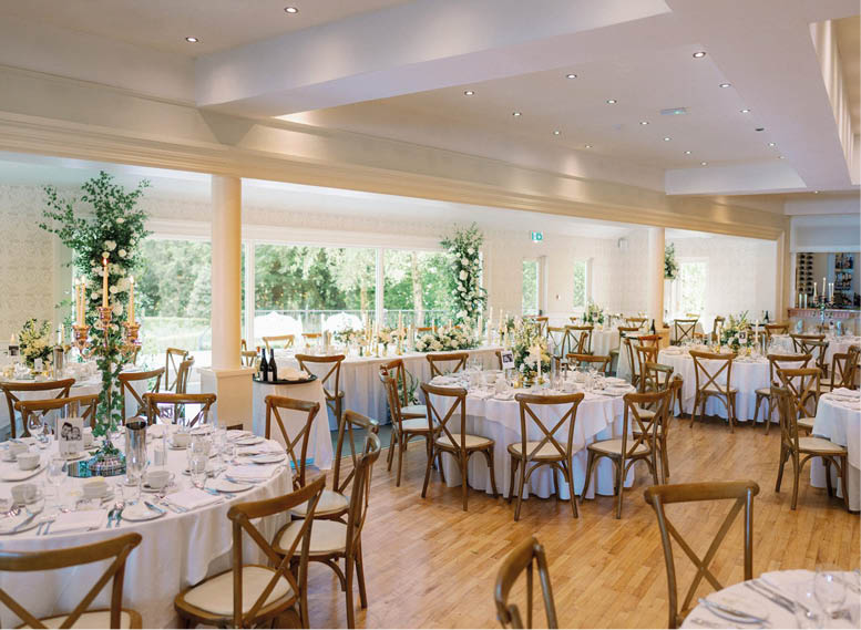 A large room with a long table set up for a wedding reception. Description generated by AI