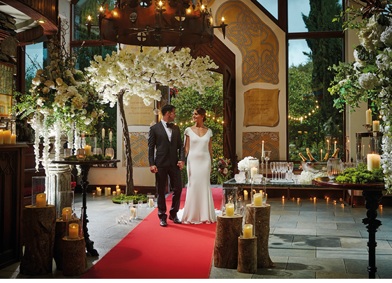 A bride and groom standing in front of a tree. Description generated by AI