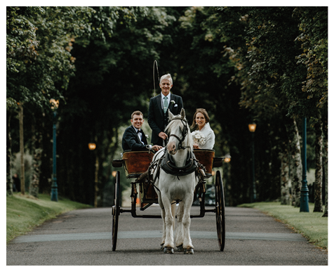 A man and woman are riding in a horse drawn carriage. Description generated by AI