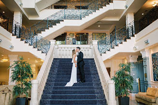 A bride and groom stand on a staircase. Description generated by AI