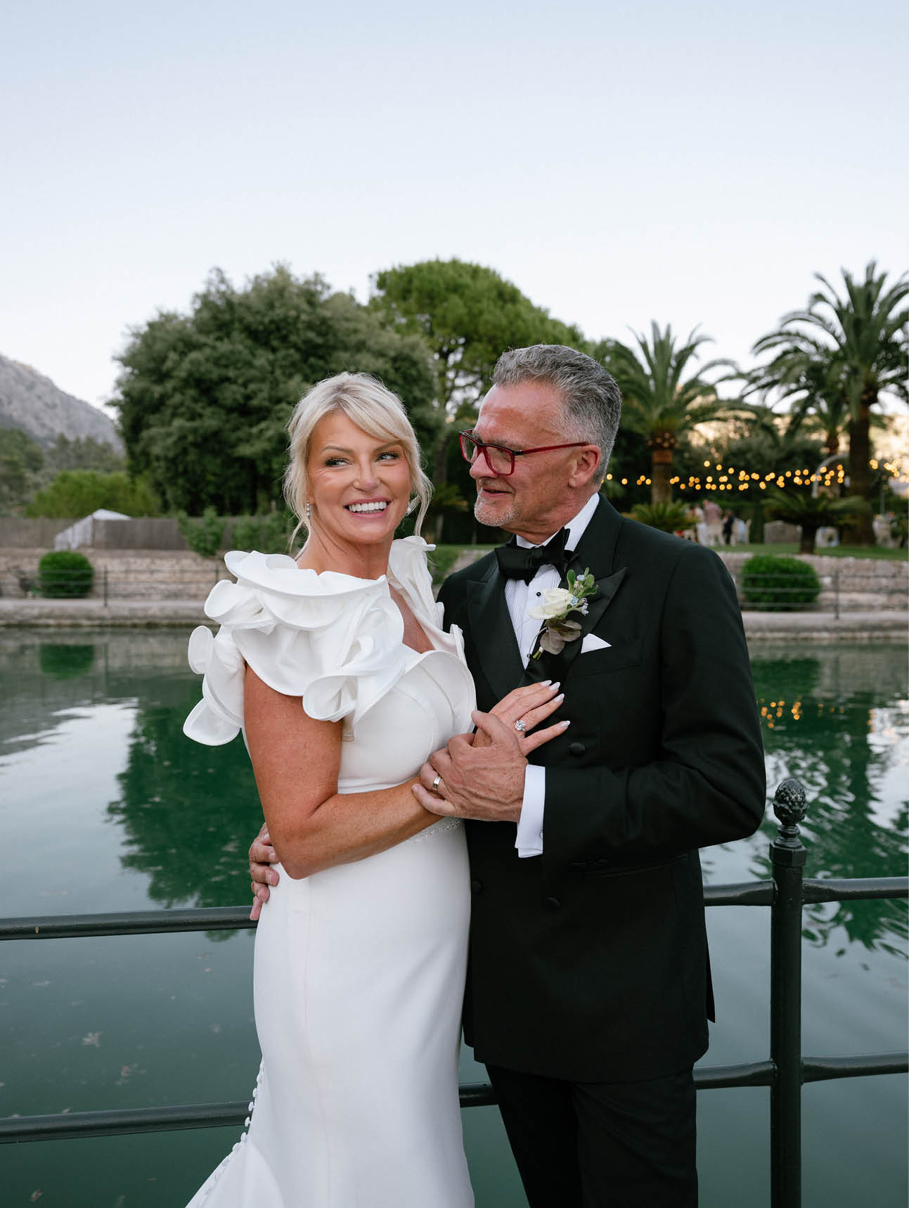 A man and woman standing together in front of a body of water. Description generated by AI