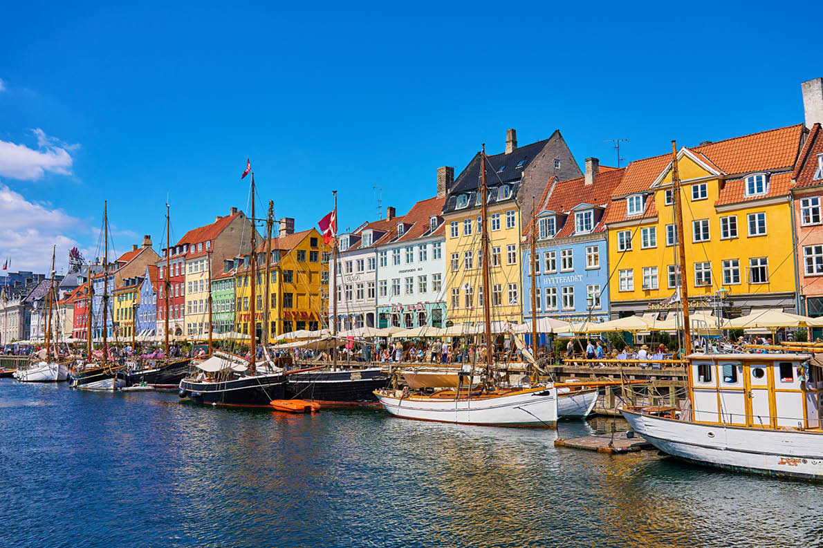 Nyhavn Harbor in Copenhagen. Famous tourist spot in Denmark with colorful historical buildings and boats on Nyhavn waterfront. Traveling in Scandinavian country. Copenhagen, Denmark - June 26, 2024