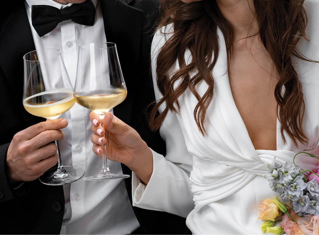 bride and groom holding wine glasses in front 