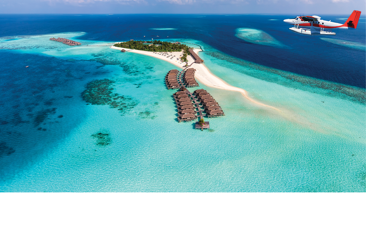 A seaplane is approaching a tropical paradise island in the Maldives with turquoise sea and sunshine