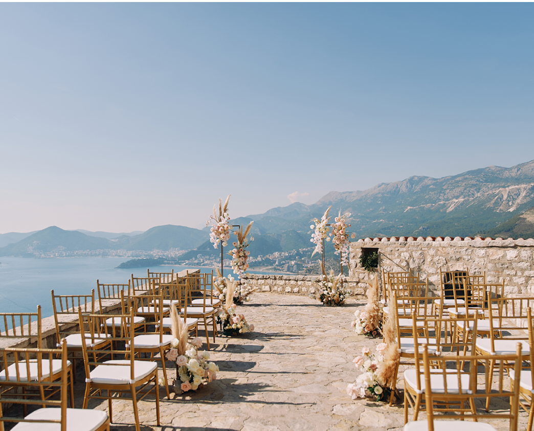 Rows of chairs stand in front of a wedding semi-arch on an observation deck over the sea