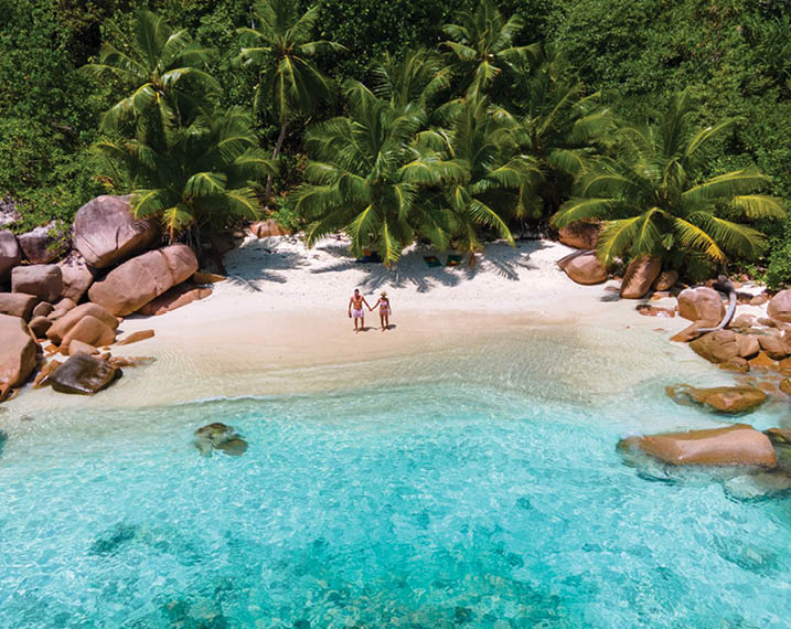 Anse Lazio Praslin Seychelles, a young couple of men and women on a tropical beach during a luxury vacation in Seychelles. Tropical beach Anse Lazio Praslin Seychelles