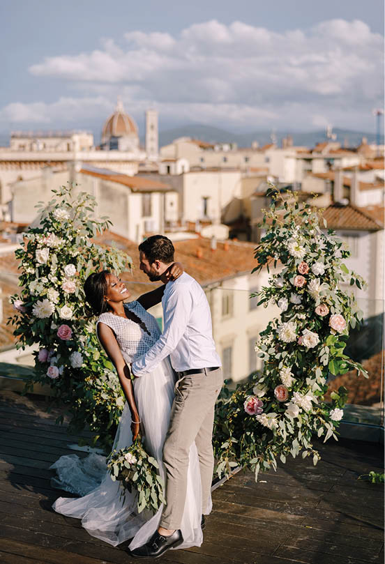 Multiracial wedding couple. Destination fine-art wedding in Florence, Italy. A wedding ceremony on the roof of the building, with cityscape views of the city and the Cathedral of Santa Maria Del Fiore
