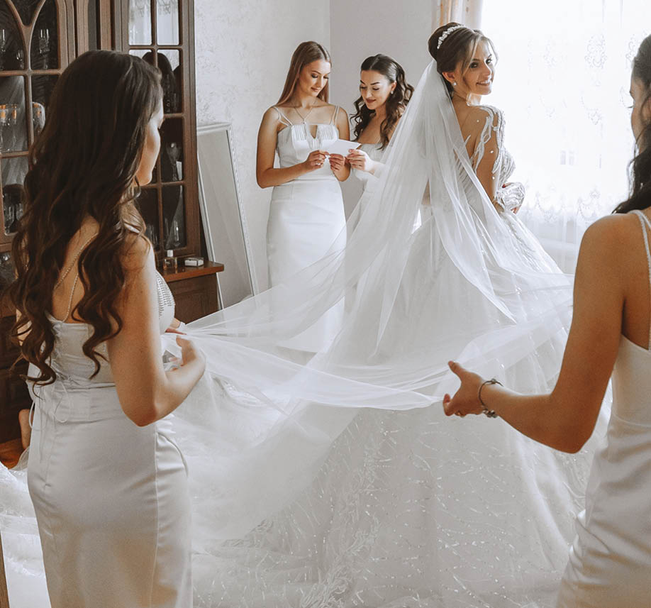 Bridesmaids rejoice in the morning, helping to fasten the buttons on the wedding dress and prepare for the wedding ceremony. They take pictures, smile, help the bride with her shoes.