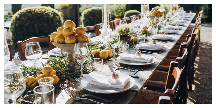 in the back yard of the old villa there is a long festive table, which is decorated with lemons and herbs, on the table are plates, glasses and candles. Wedding in Italy. Tuscany