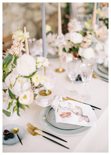 Knotted colorful napkin lies on a plate on the table next to a bouquet of flowers and cutlery