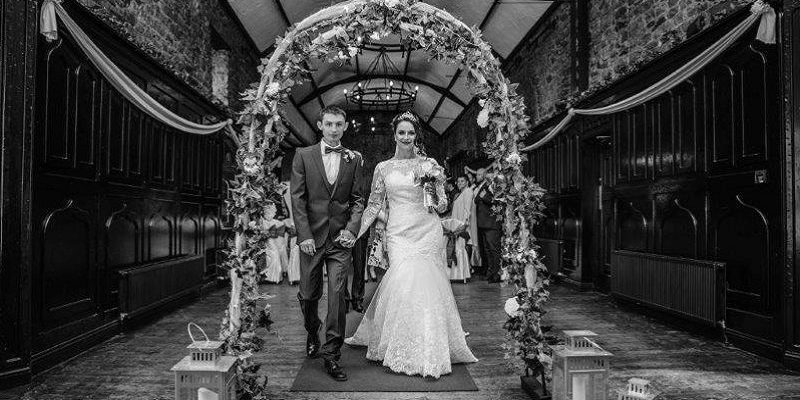 bride and groom under flower arch