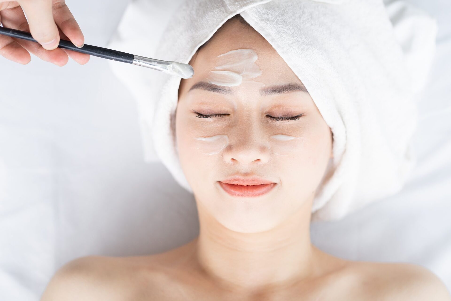 This is an image of a woman getting a facial. Skincare is being applied.