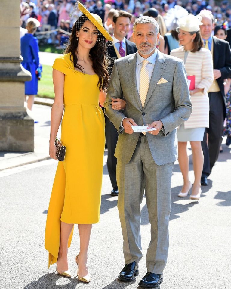 Amal and George Clooney at Harry and Meghan Markle's wedding in 2018. Featured image for article titled Our Favourite Celebrity Wedding Guest Looks