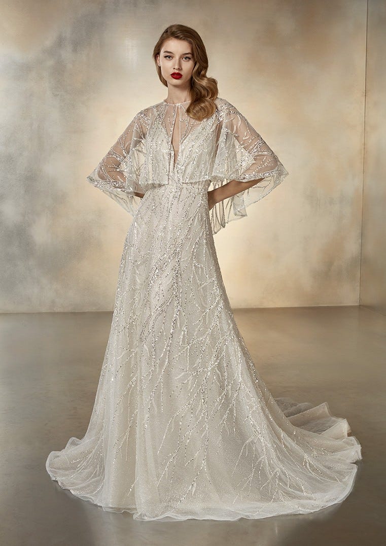 This image shows a bride in her wedding dress with a short cape from Pronovias as a cover-up.