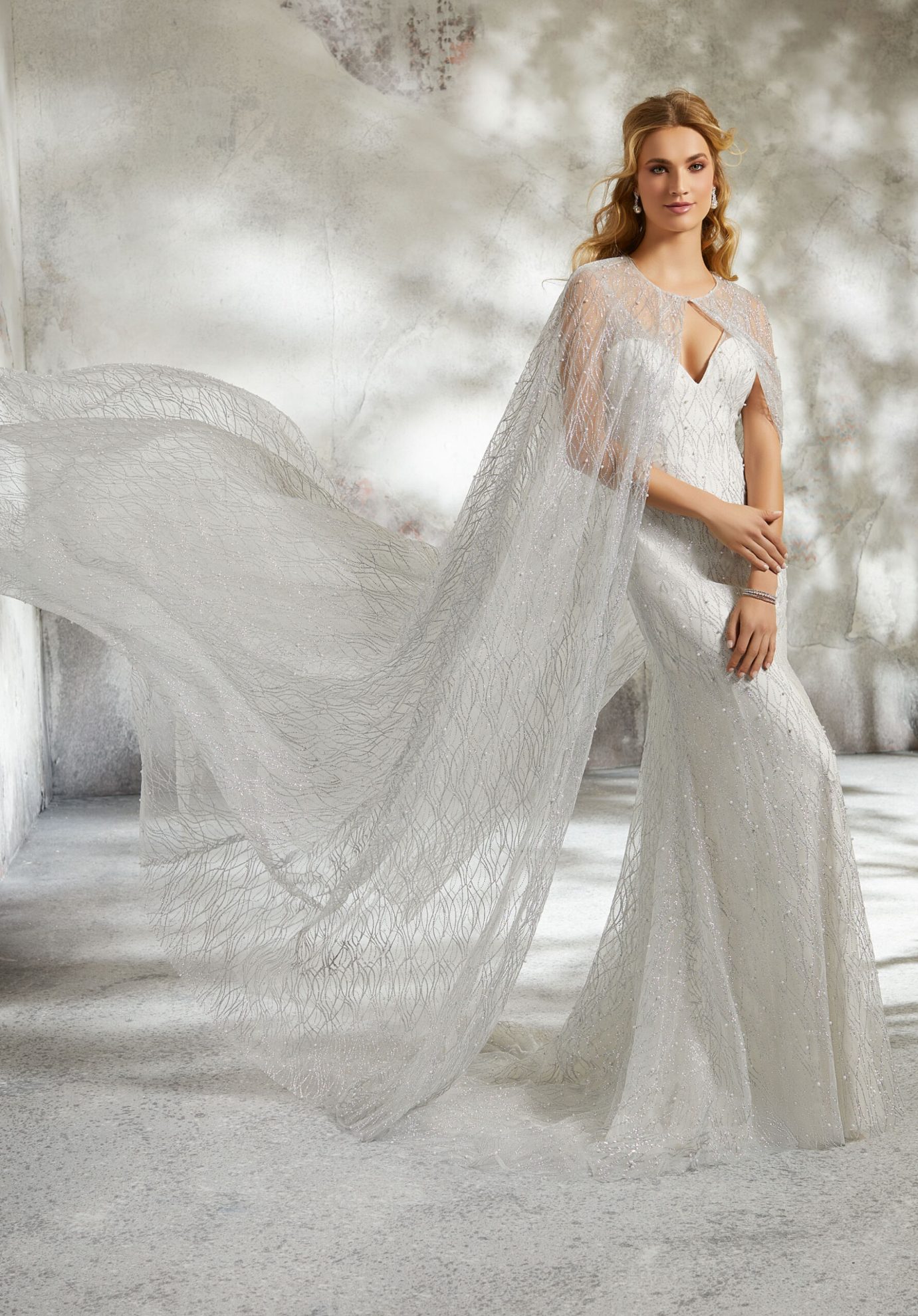 This image shows a beautiful bride in her wedding dress with a Morilee cape as a bridal cover-up.