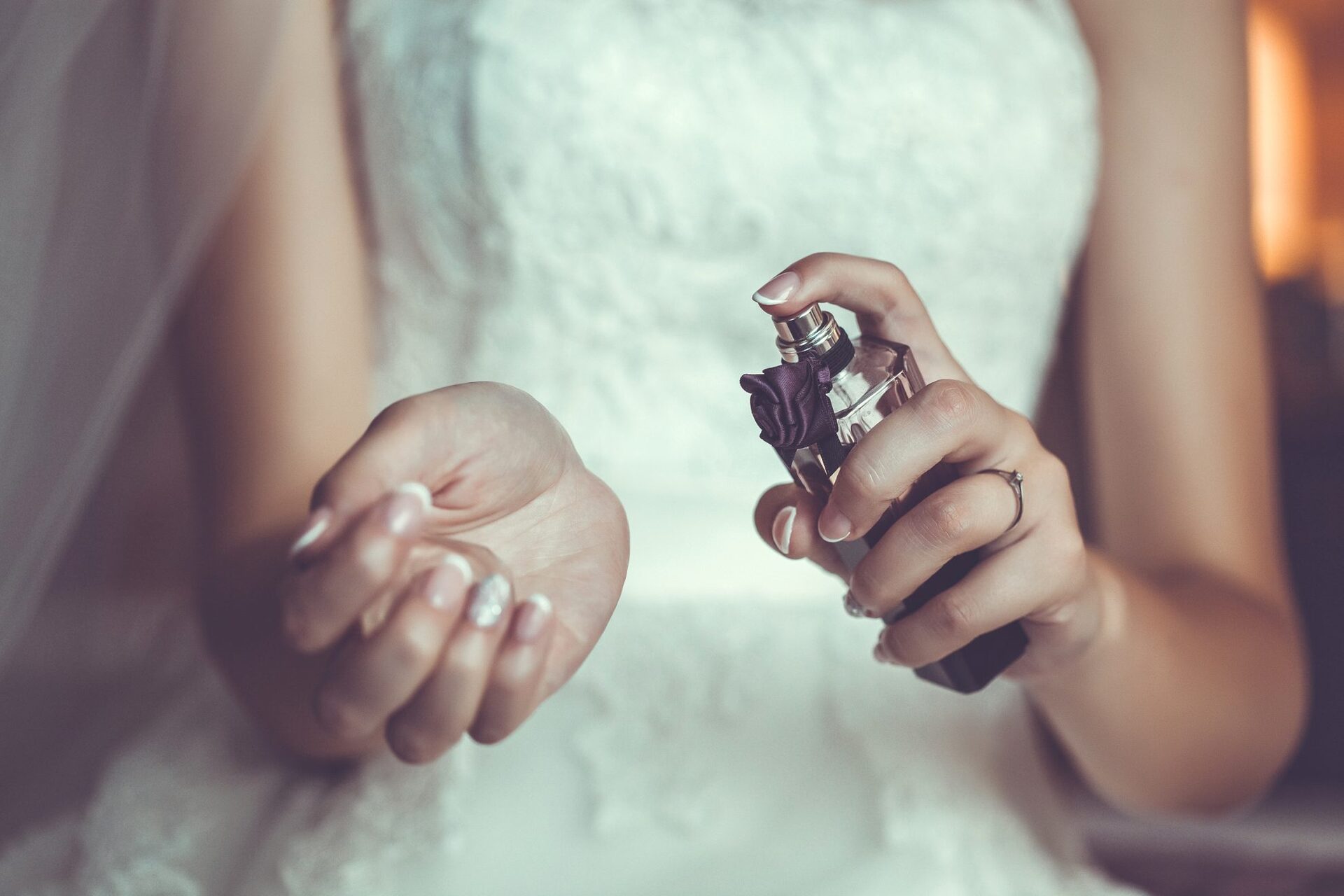 A close-up of a bride spraying perfume on her wrist, Image used in the Everything You Need For A Wedding Day Emergency Kit article.