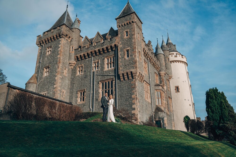 An image of a bride and groom standing outside their wedding venue. Image featured in the 37 Questions To Ask Your Wedding Photographer article.