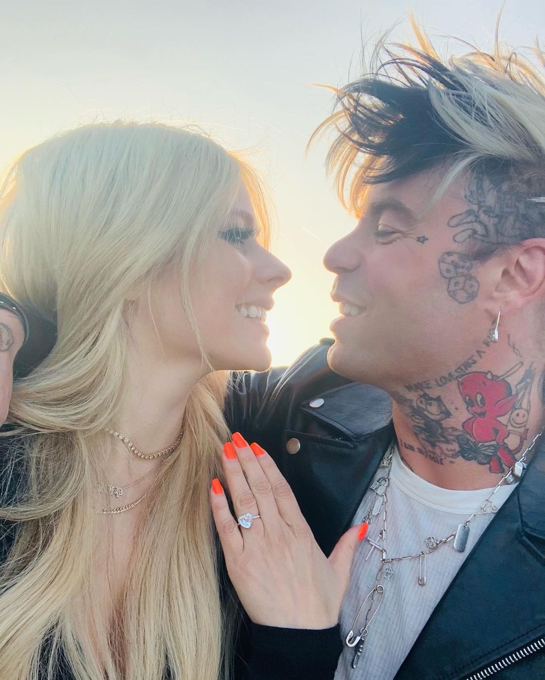 Avril Lavigne and Mod Sun looks into each others as Avril shows her heart-shaped diamond engagement ring.