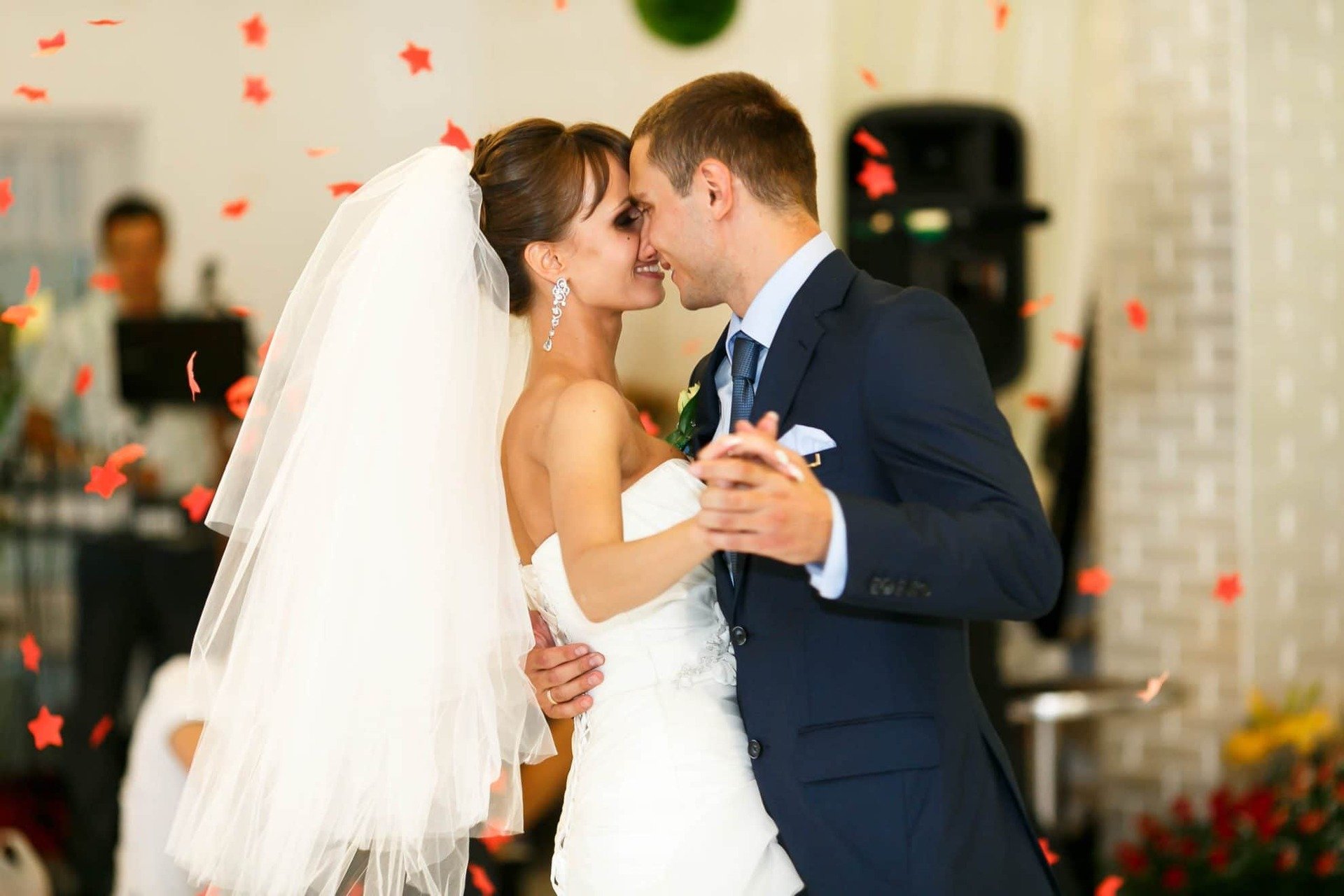 Bride and groom during their first dance. Red confetti in a star shape fall from above.