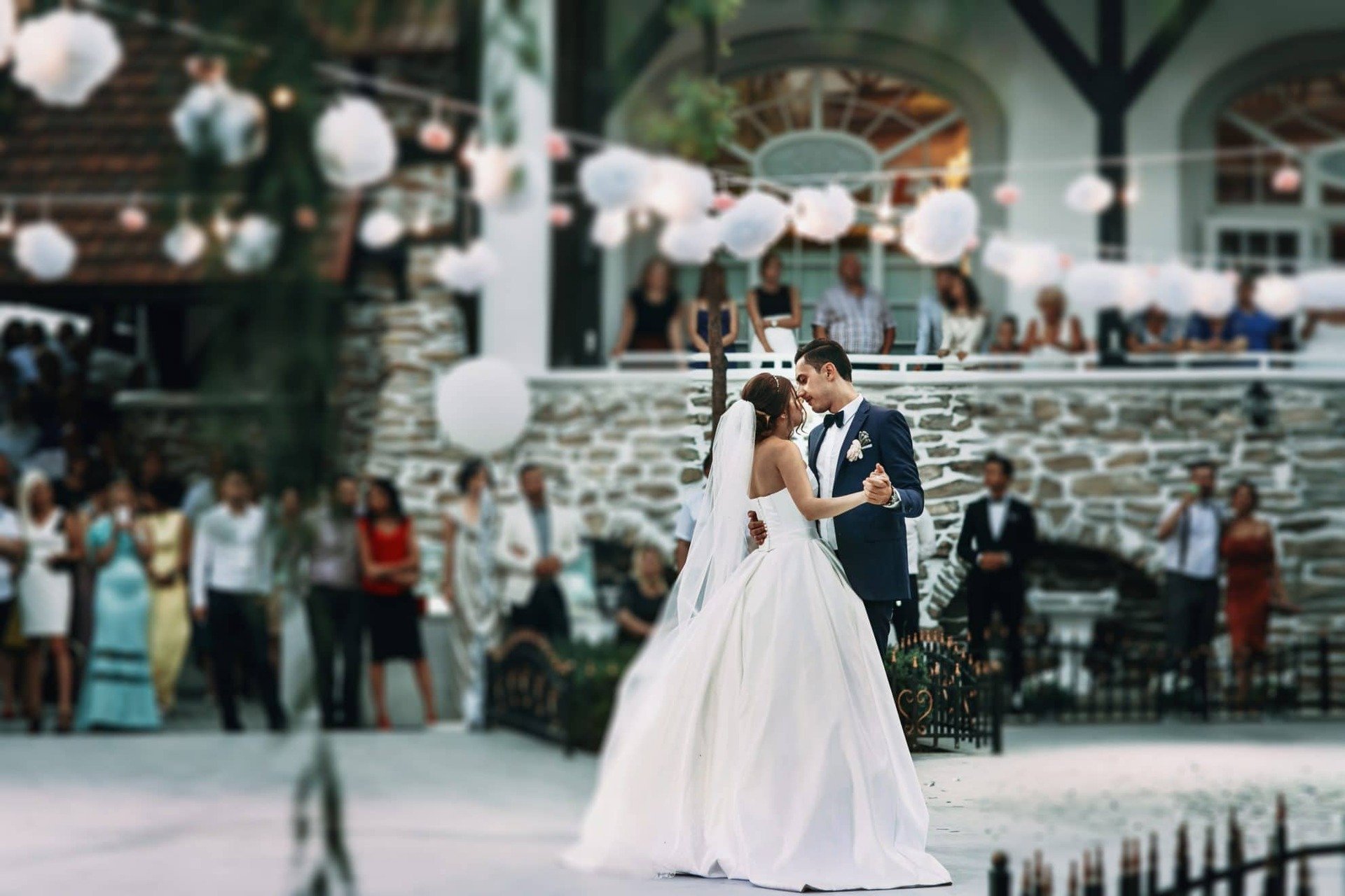 Bride and Groom during their first dance. Guests watch and lanterns can be seen overhead. Image used in the 33 Of The Best First Dance Wedding Songs.