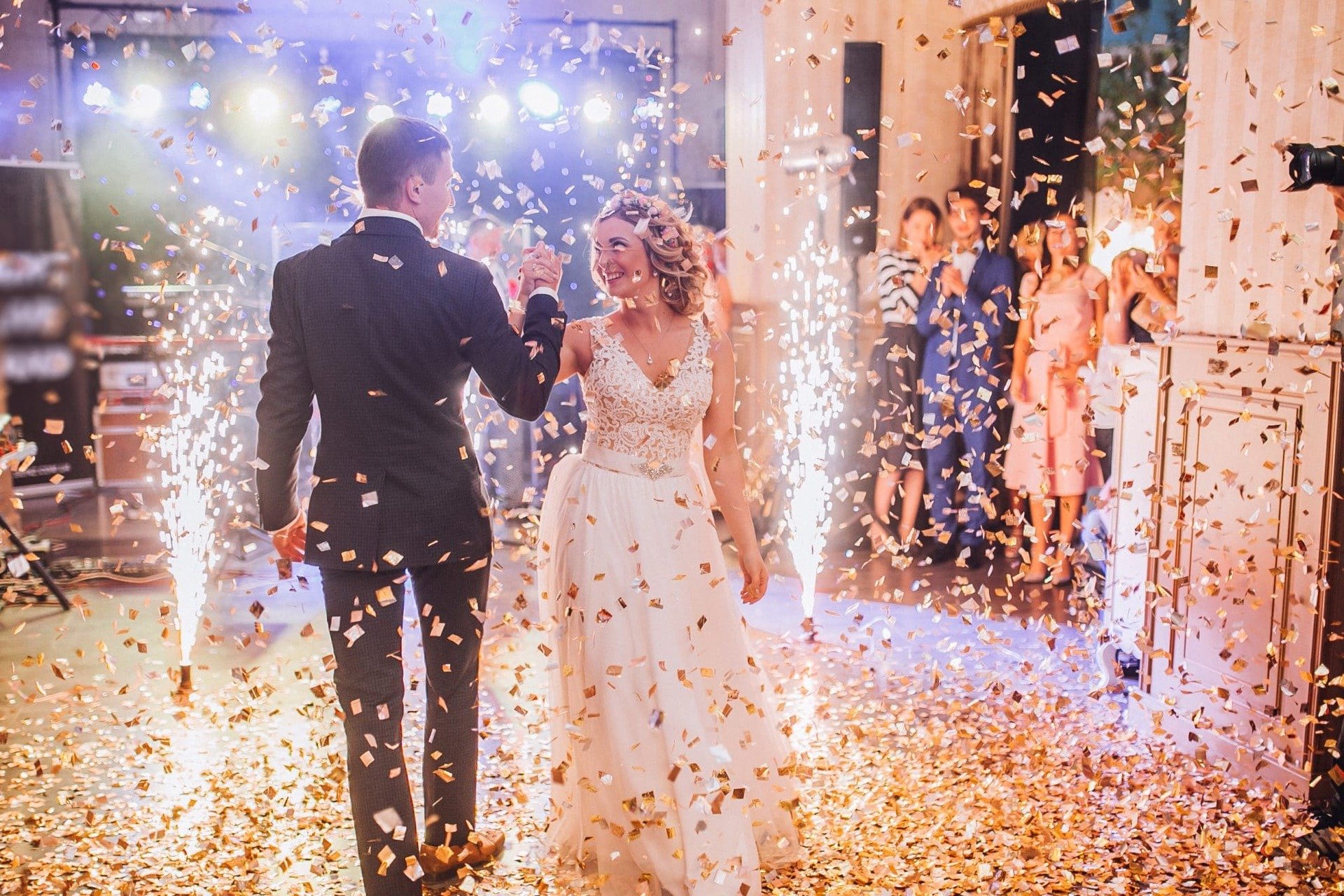 Bride and groom on the dancefloor as guests watch. Confetti and sparklers can be seen in the background. Image used in the 33 Of The Best First Dance Wedding Songs article.