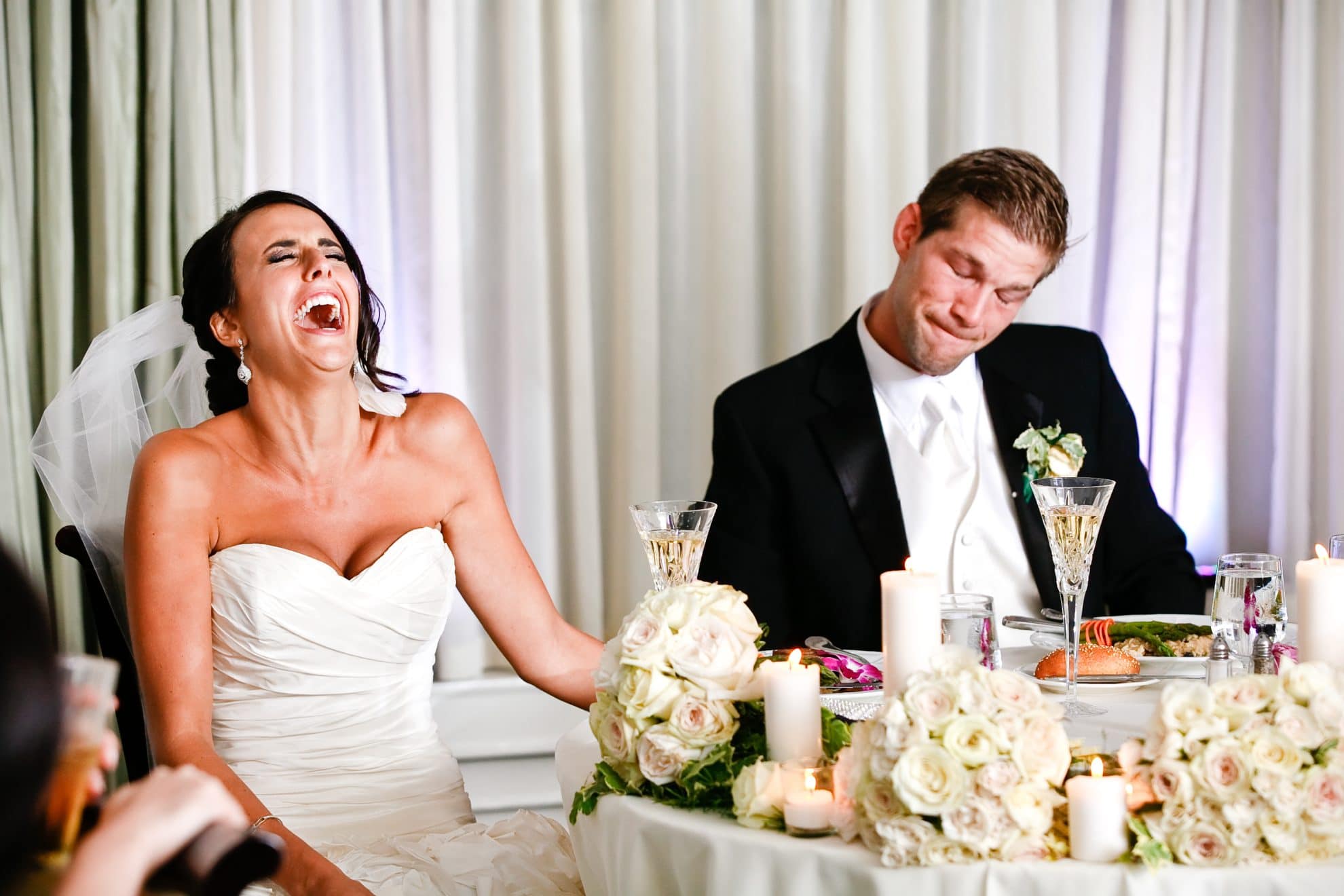 A bride is seen laughing while sitting at the table.