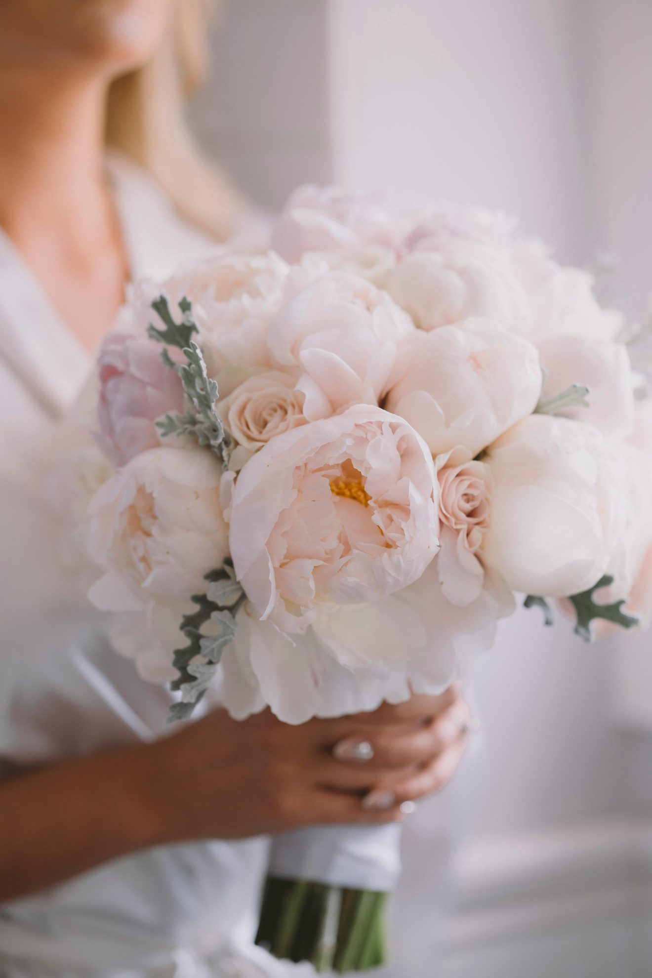 A bride holding a bouquet of peonies